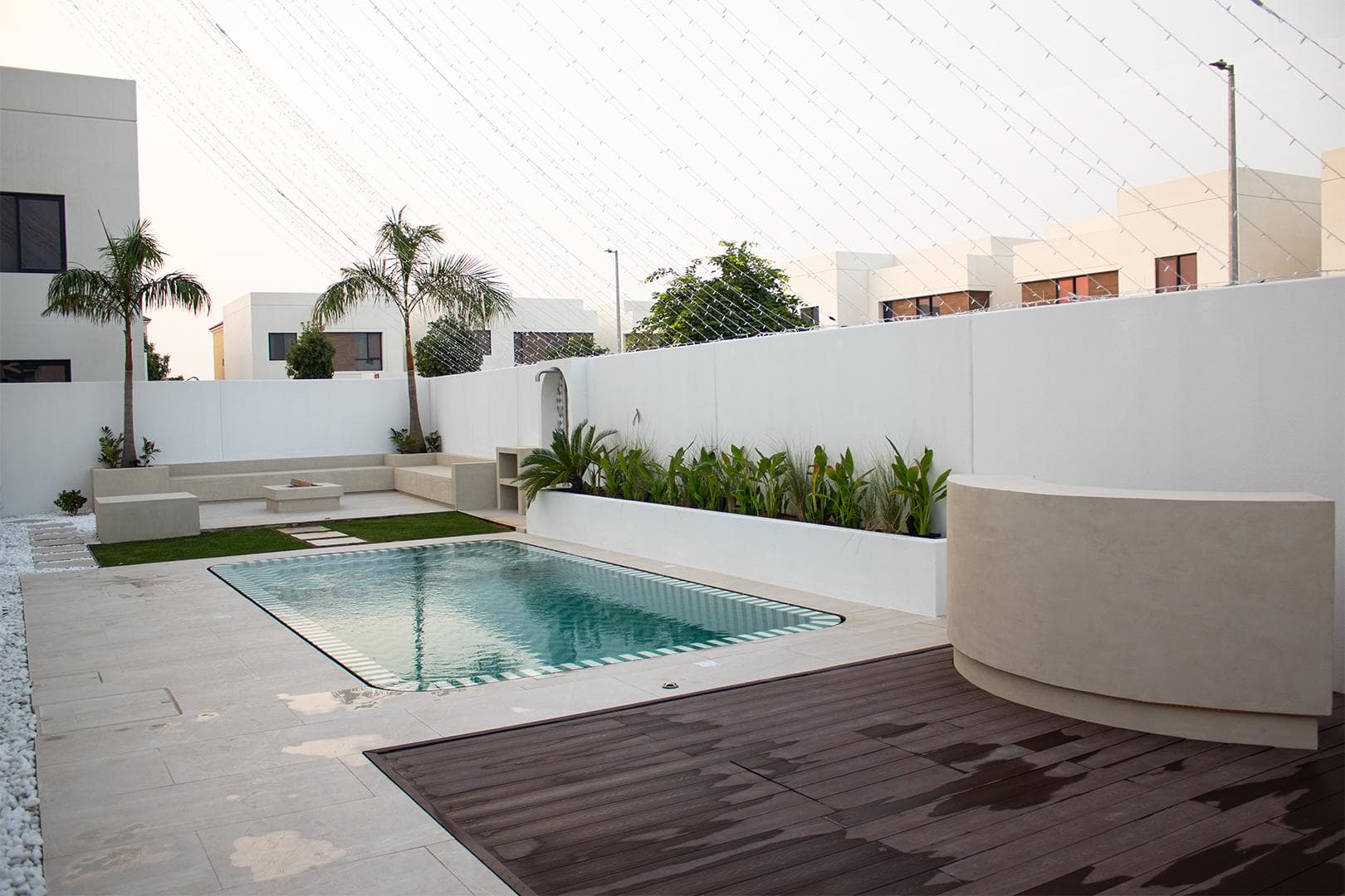 Pool terrace with a curved rendered wall and timber decking, built by Eagle at a villa in Abu Dhabi