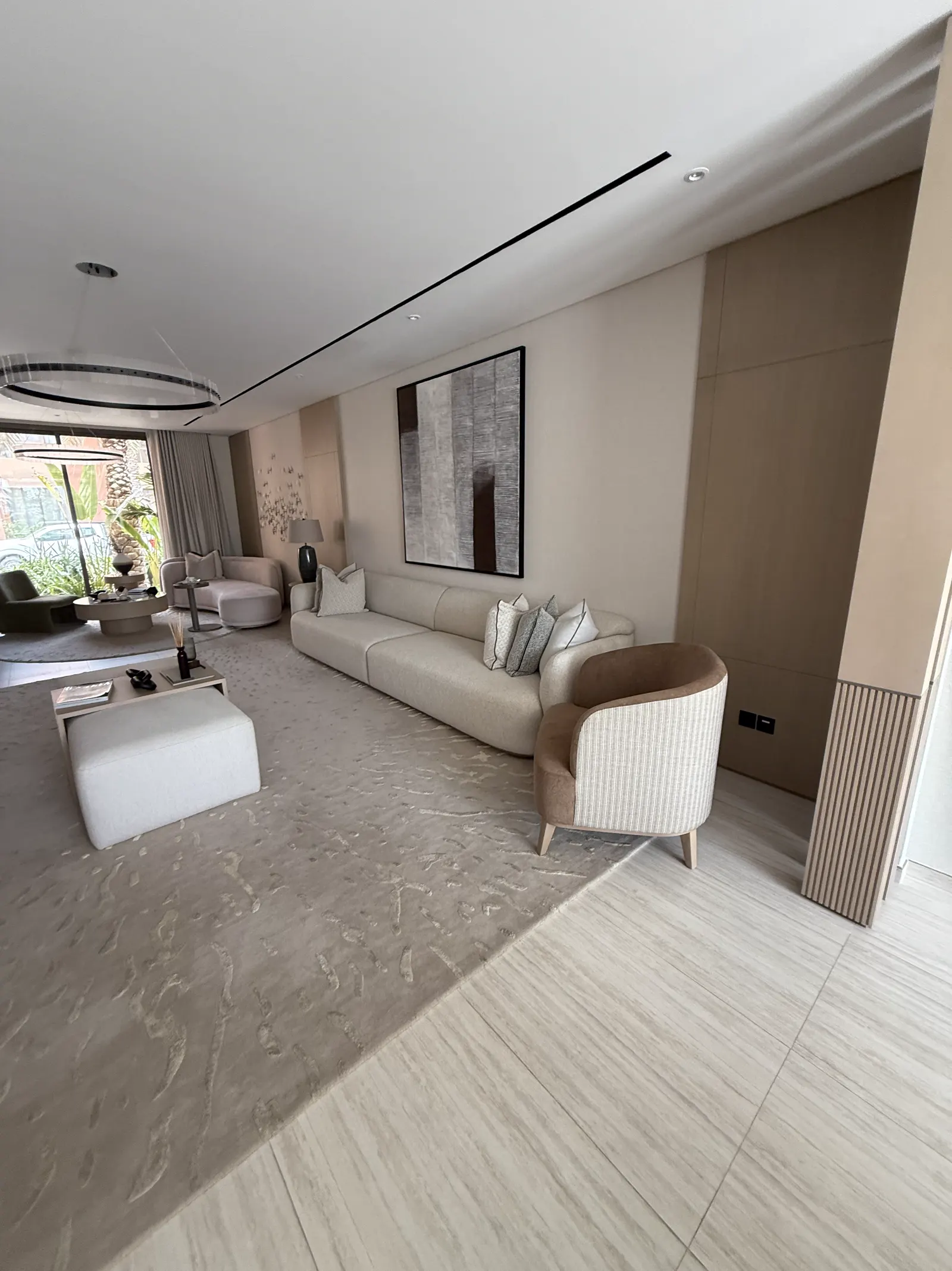 Living room with curved sofa, ring pendant and garden view through full-height glazing