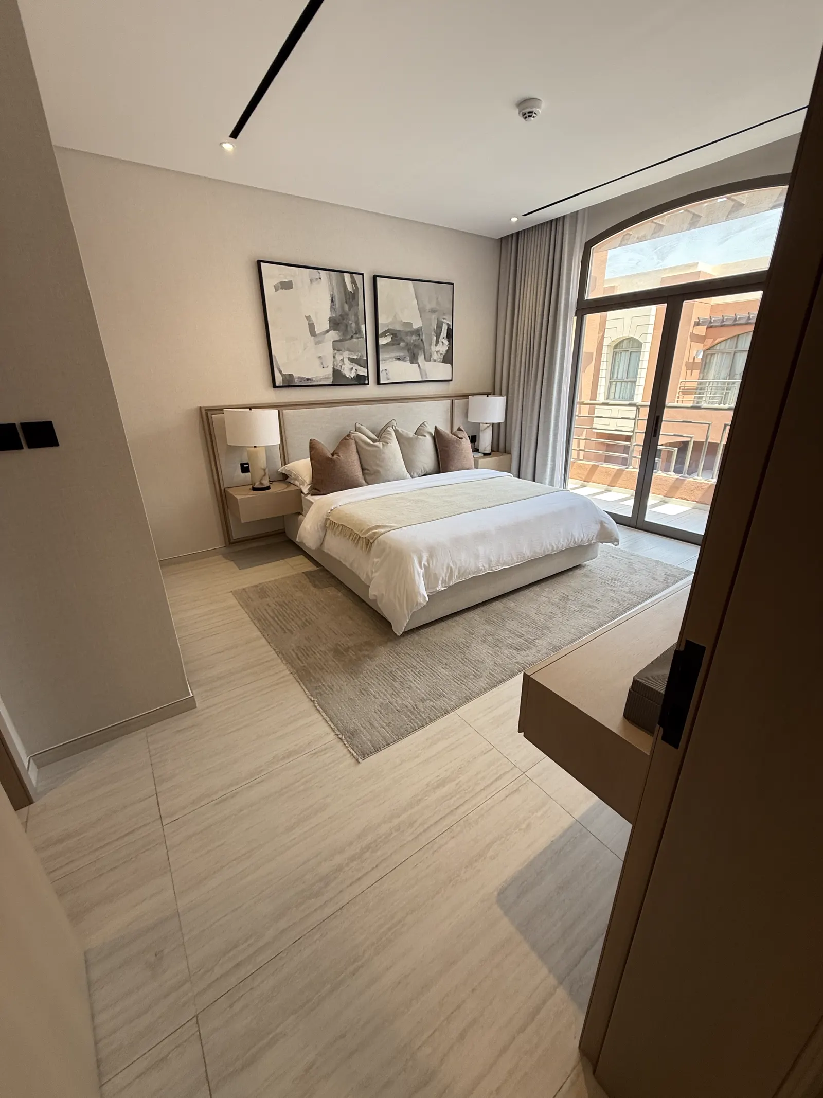 Bedroom with upholstered headboard wall, framed artwork and arched window