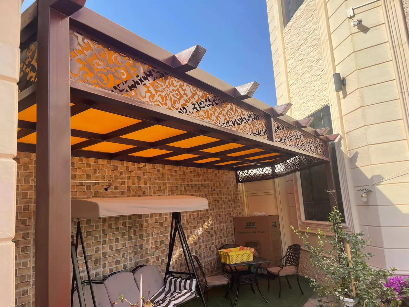 Covered outdoor lounge with a swing seat, patterned tile wall and garden furniture
