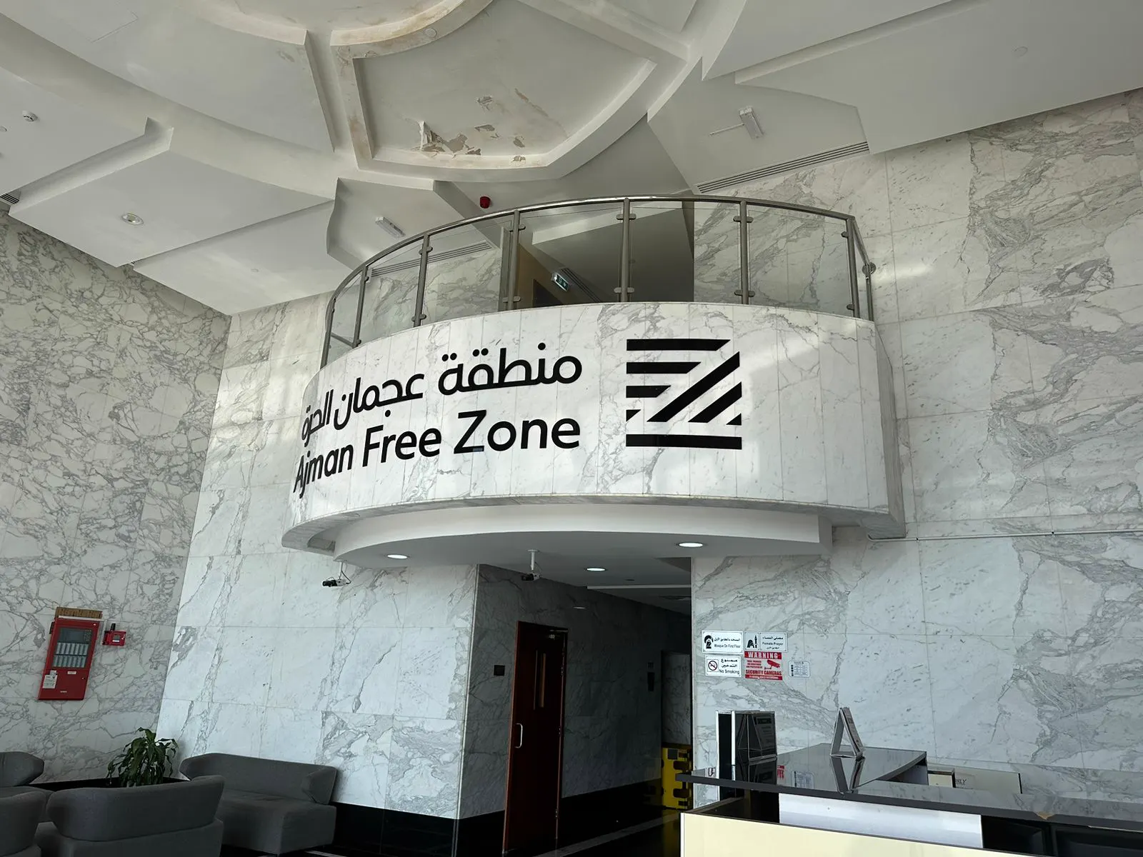 Ajman Free Zone reception with curved marble desk surround and branded signage