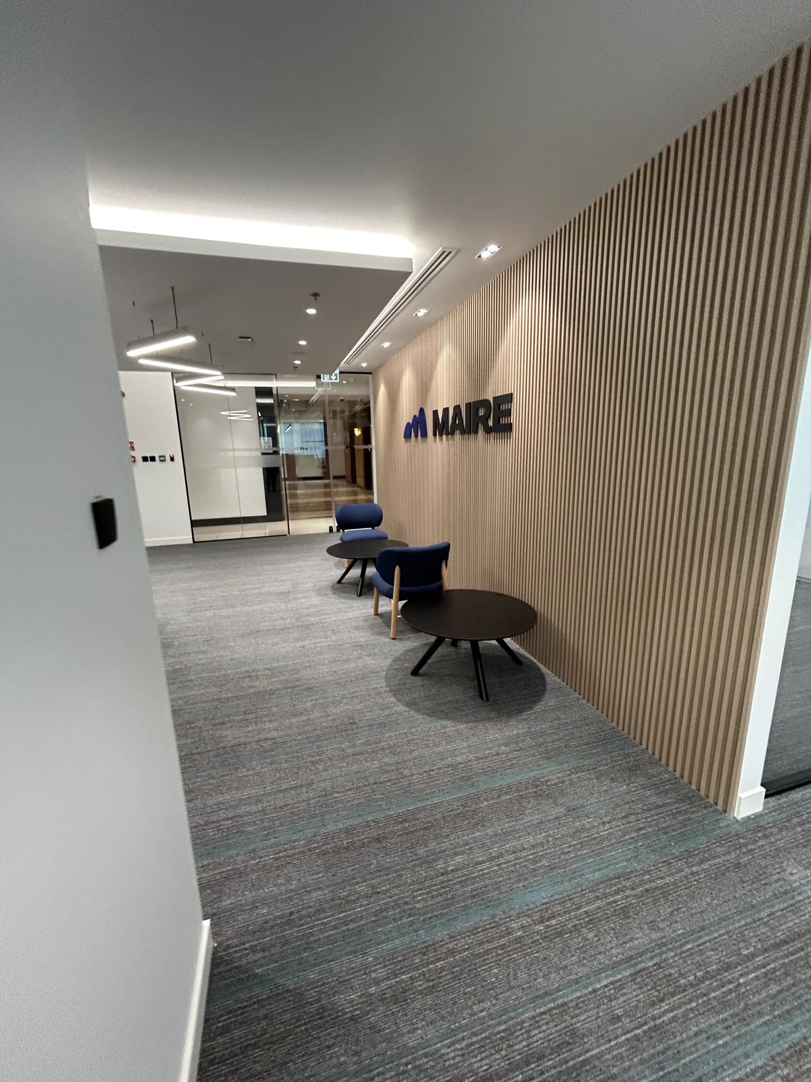 Office corridor lined with a timber slat wall and recessed linear lighting