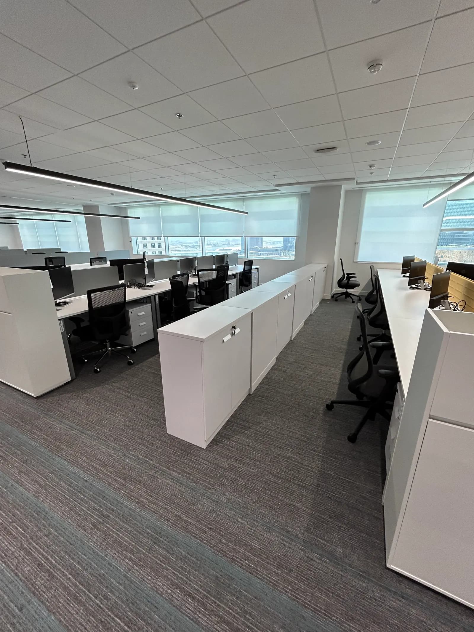 Open-plan office with white storage units, task seating and glazed perimeter