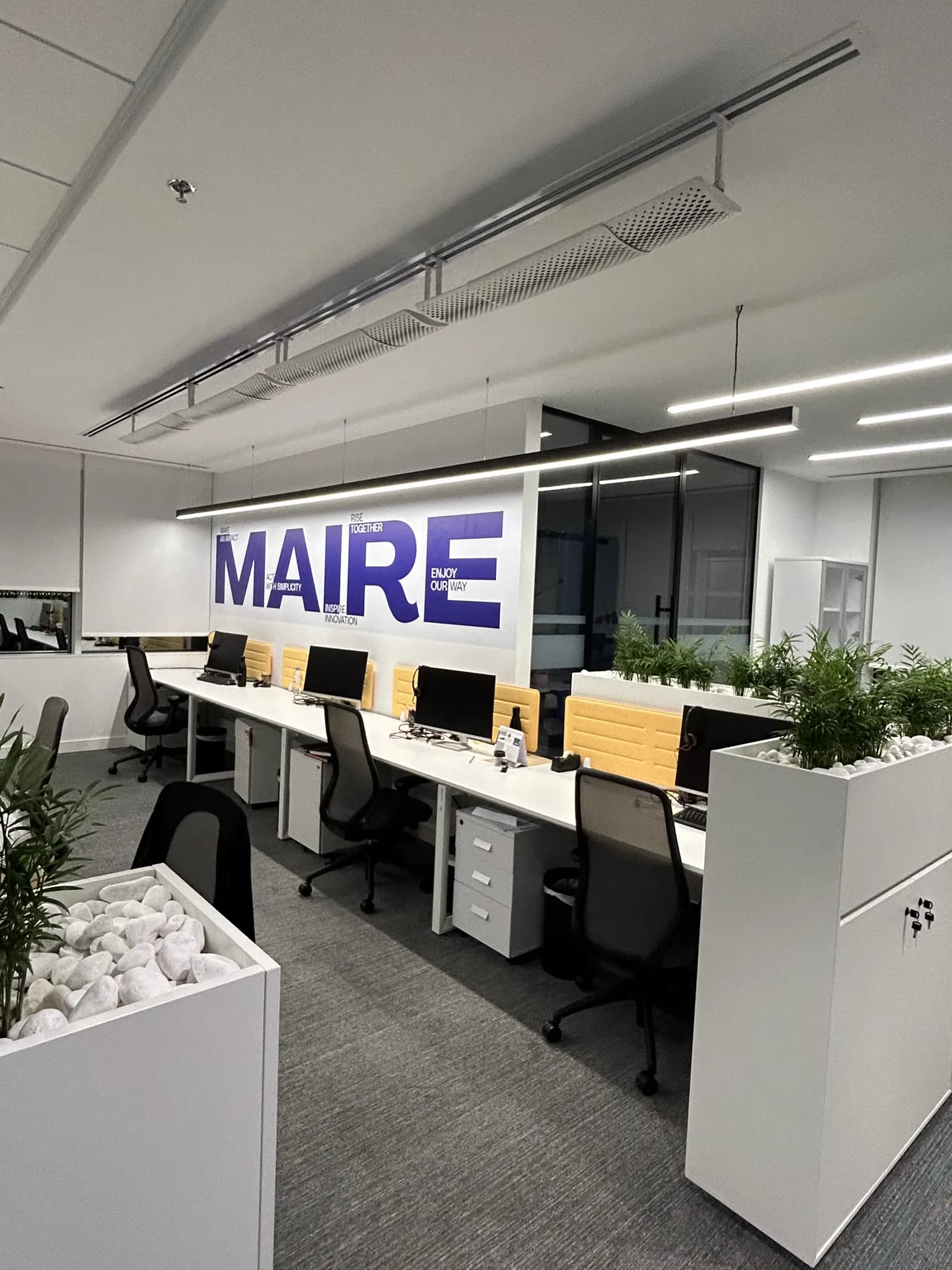 Maire Tecnimont workspace with brand wall, planted dividers and pendant lighting