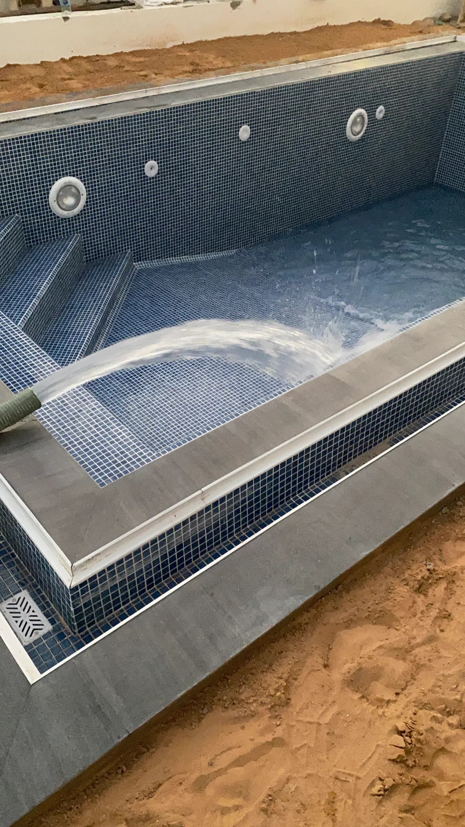 Water spilling over the mosaic-tiled overflow channel of a swimming pool