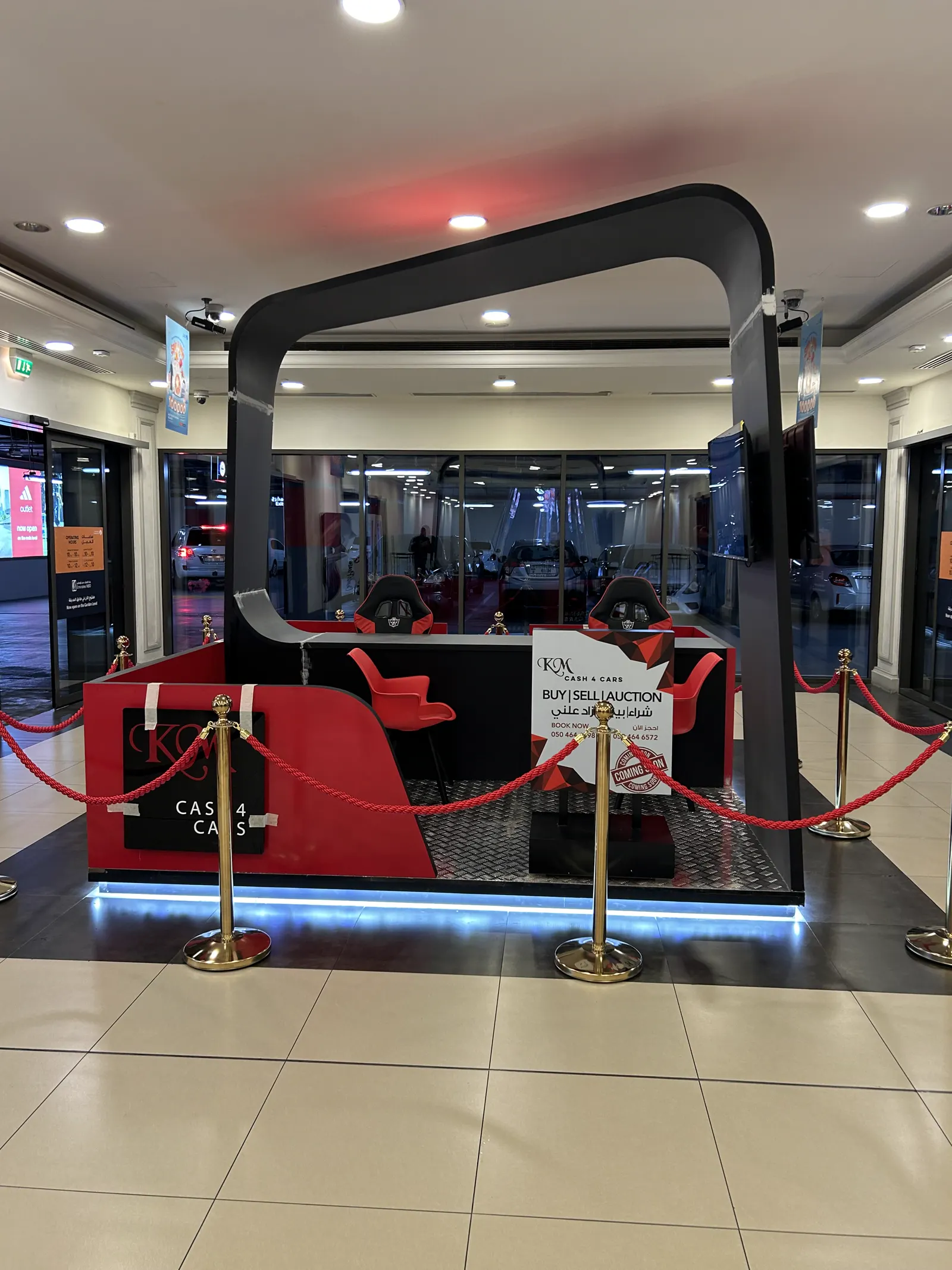 Mall retail kiosk with illuminated plinth, brand arch and rope barriers