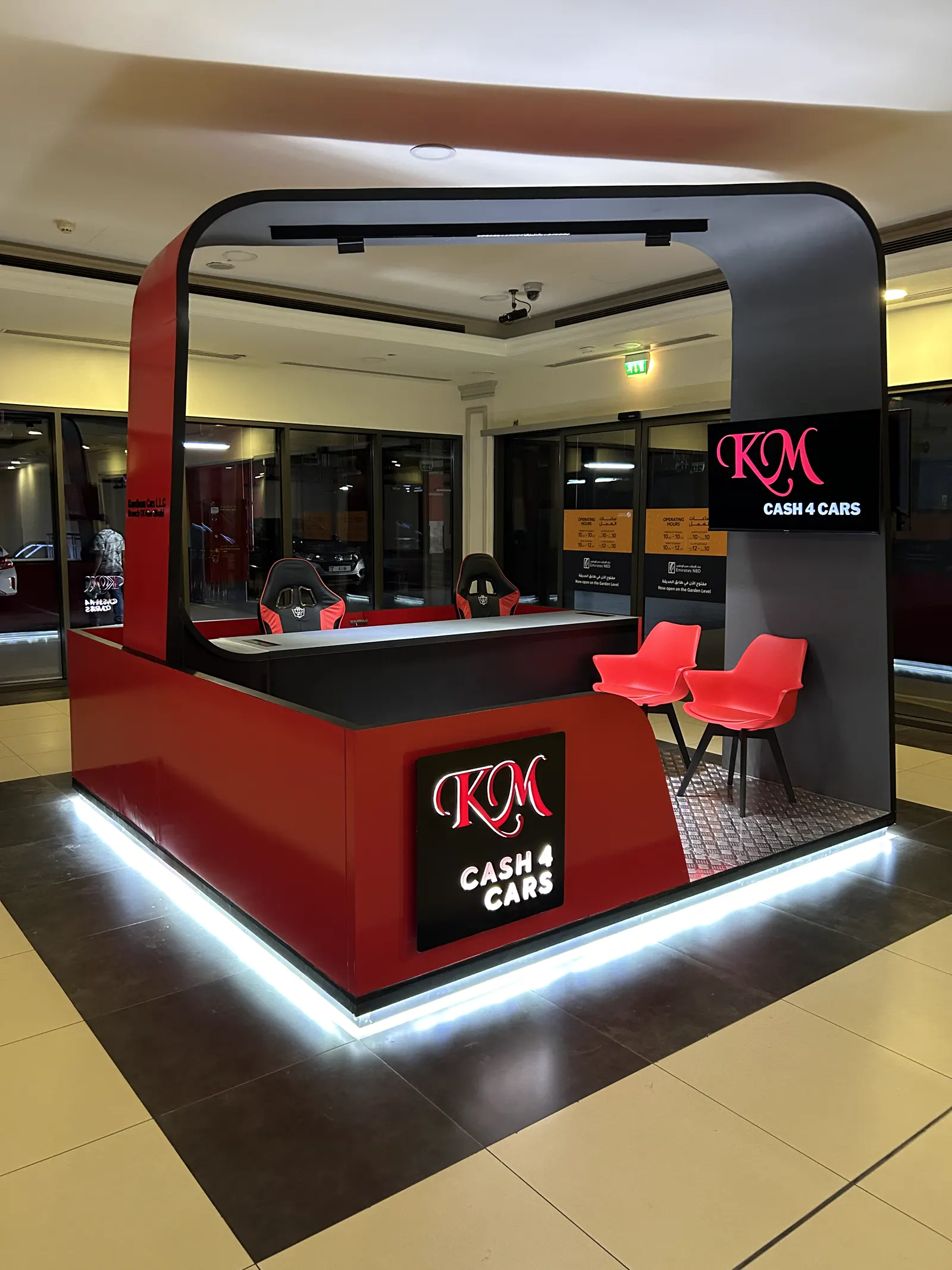 Retail counter with backlit base, brand panel and red seating